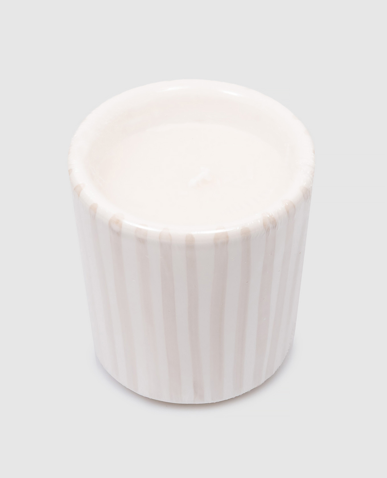 A white scented candle in a beige striped ceramic candle holder with a logo